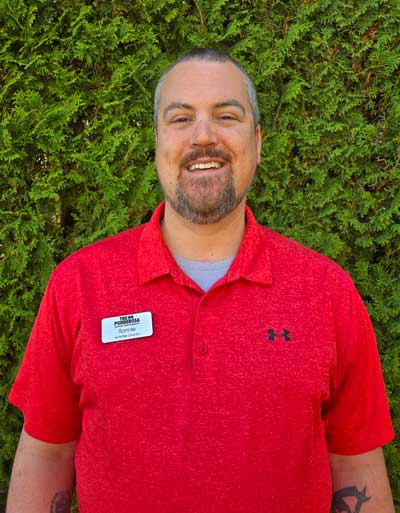 Staff member smiling in front of greenery