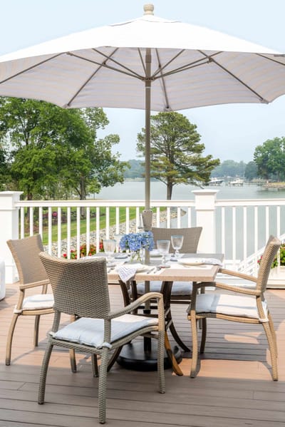 Outdoor dining setup by the lake with umbrella and chairs