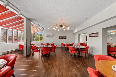 Bright dining room with red chairs and large windows