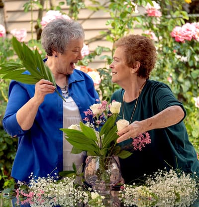 Two residents enjoying a flower arranging activity outdoors
