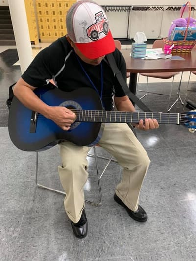 Resident playing guitar in an indoor activity area