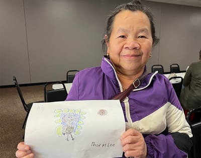 A resident proudly holding a colorful turkey drawing