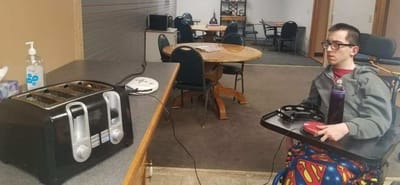 Resident seated in a common area with a toaster.
