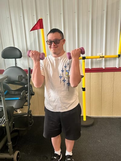 A resident exercising with dumbbells in a gym area