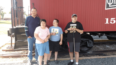 Group of four individuals outdoors next to a train car
