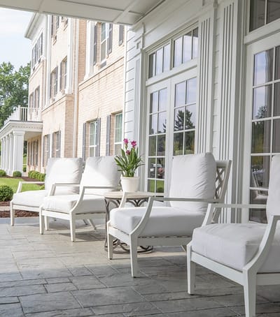 Outdoor seating area with white chairs and a potted plant