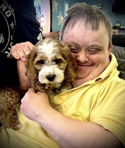 Resident smiling with a puppy in a cozy setting