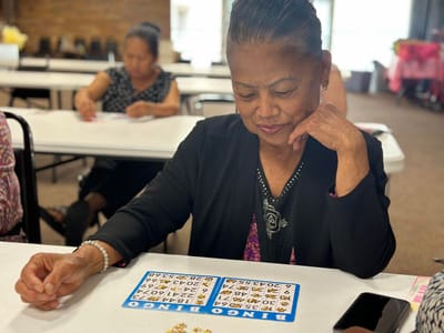 Resident focused on a Bingo game at a common area table.