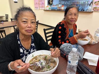 Two women enjoying bowls of pho in a dining area