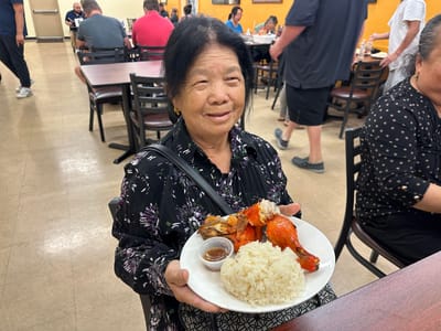 A resident holding a plate of food in a dining area
