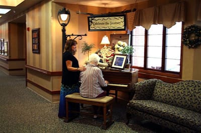 Residents interacting around a piano in a hallway