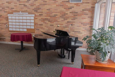 Interior of a common area with a piano and tables