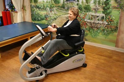 Resident exercising on a fitness machine in an activity room