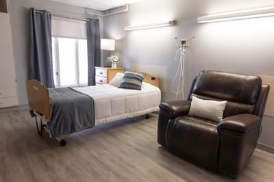 A well-furnished resident room with a bed and chair