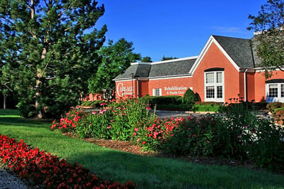 Exterior view of Care Age rehab center surrounded by flowers