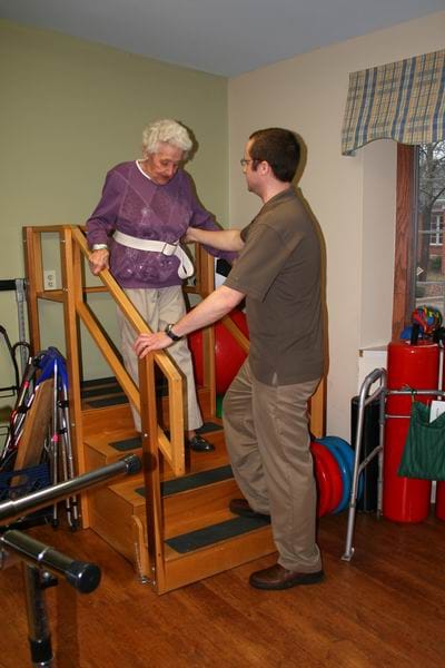 A staff member assisting a resident on stairs