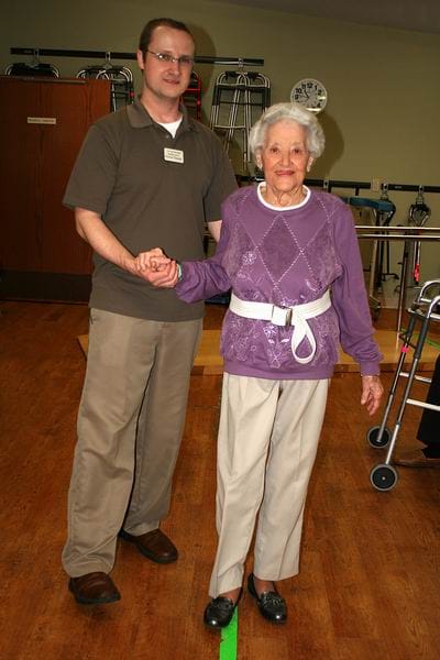 A staff member assisting a resident in a rehabilitation area