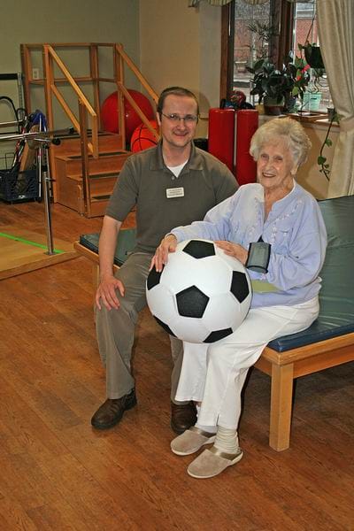 Staff member and resident playing with a soccer ball indoors