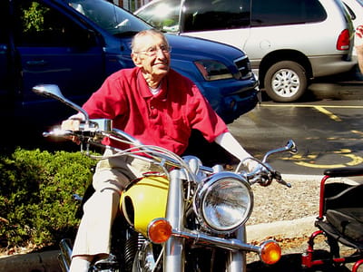 Elderly man enjoying a motorcycle outside