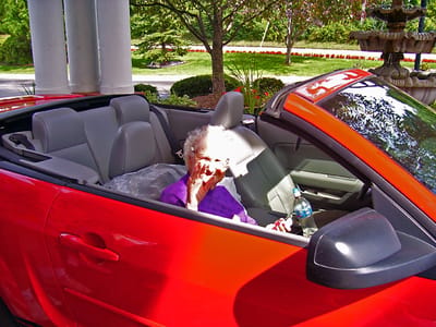 Elderly woman enjoying a drive in a red convertible car