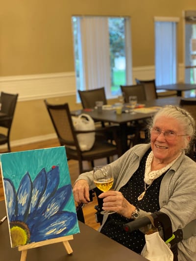 Resident painting with a drink in hand during an activity