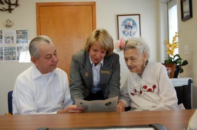 A staff member assisting two residents with a brochure