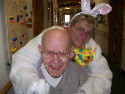 Resident and staff member celebrating together in a hallway