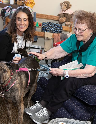 Staff member and resident interacting with a dog
