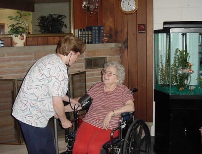Nurse taking a resident's blood pressure in a common area