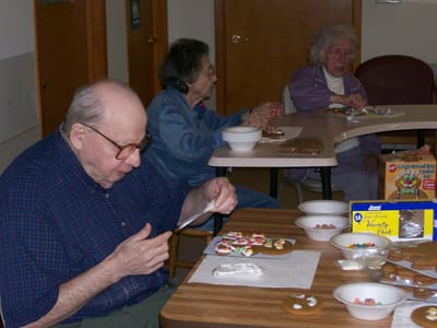 Residents decorating gingerbread cookies in a common area