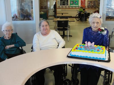 Residents celebrating a 104th birthday with a cake