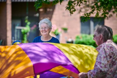 Residents enjoying a bright outdoor activity with a colorful parachute
