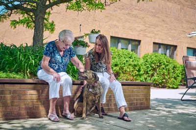 Resident and staff enjoying time outdoors with a dog