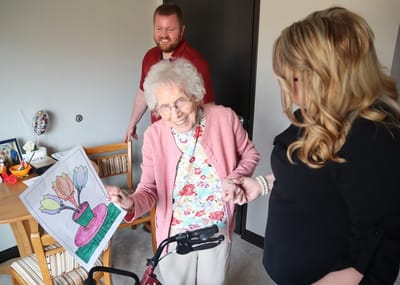 Resident proudly holding artwork with staff present