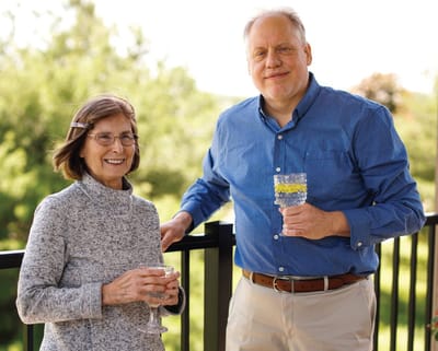 Residents enjoying drinks on a balcony with a green backdrop