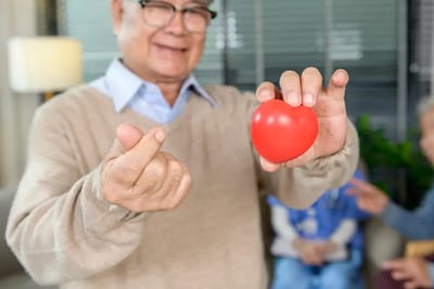 Elderly man holding a red heart stress ball in a common area