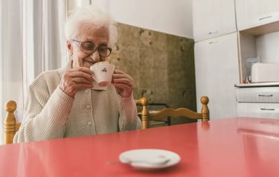 Elderly woman enjoying a warm drink at a table