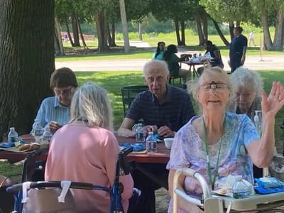 Residents enjoying lunch outside at picnic tables.