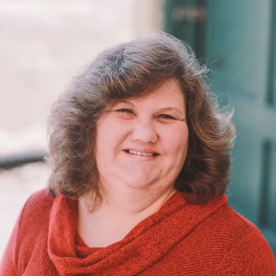 A smiling staff member in a red sweater