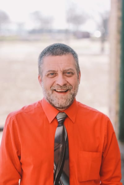 A staff member smiling in an orange shirt