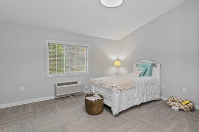 Bright, cozy resident room with a bed and lamp