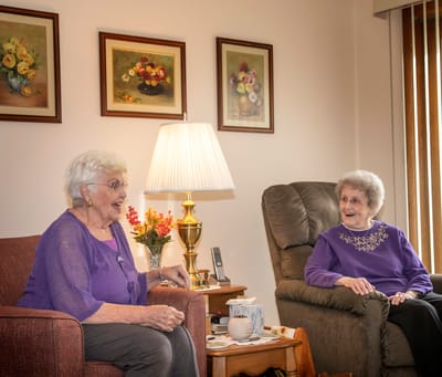 Two residents enjoying conversation in a cozy common area