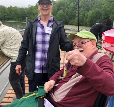 A staff member and a resident fishing by a lake