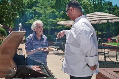 Senior resident interacting with a staff member at a barbecue