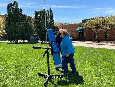 Resident enjoying a telescope in the garden with staff assistance