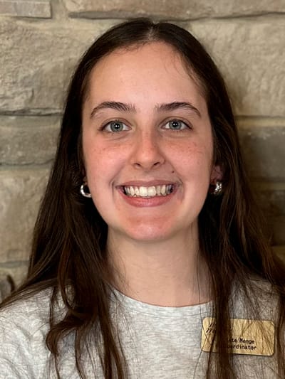 Staff member smiling in front of a stone wall
