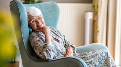 Older woman smiling in a cozy chair indoors