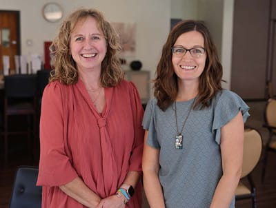 Two staff members smiling in a common area