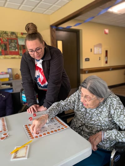 Residents playing bingo with staff assistance