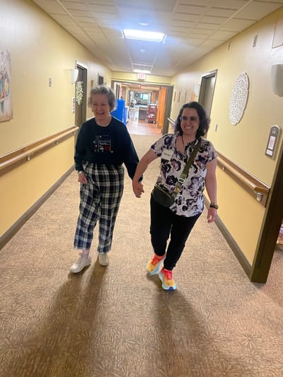 Two women walking hand-in-hand down a hallway